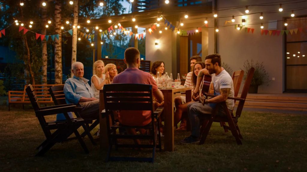 Guests dining outdoors beneath string lights