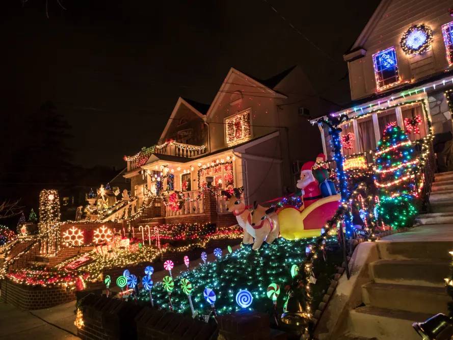 Multicolored holiday lights across porches, shrubs and yard displays