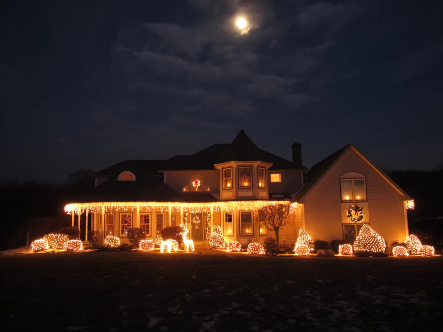 Warm white holiday lights outlining a home and its front garden