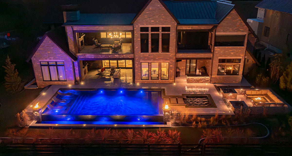 Blue pool lighting and purple accent lights beside a home