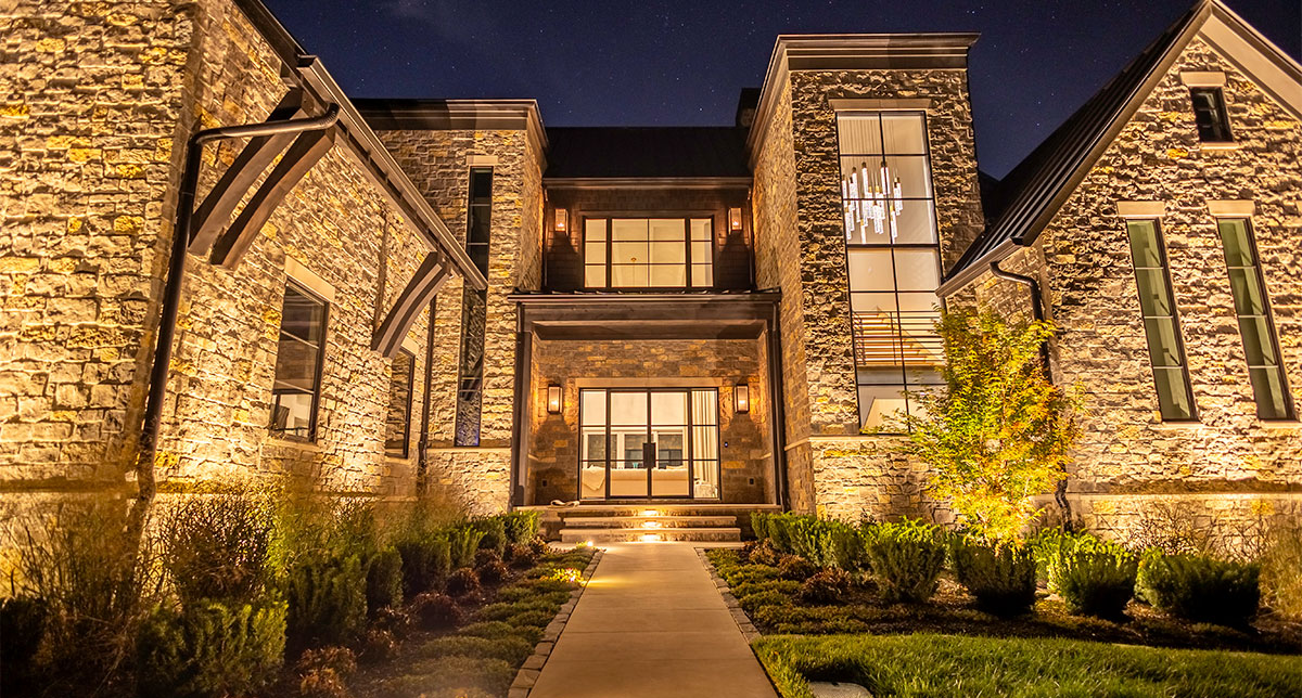 Warm lighting highlighting stone walls and an entry garden