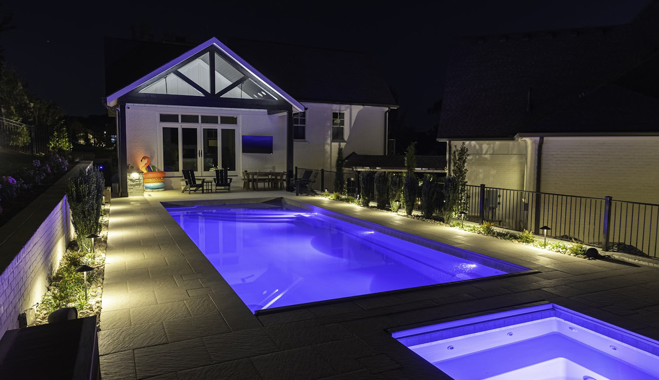 Pool and spa with purple underwater lighting and lit paths
