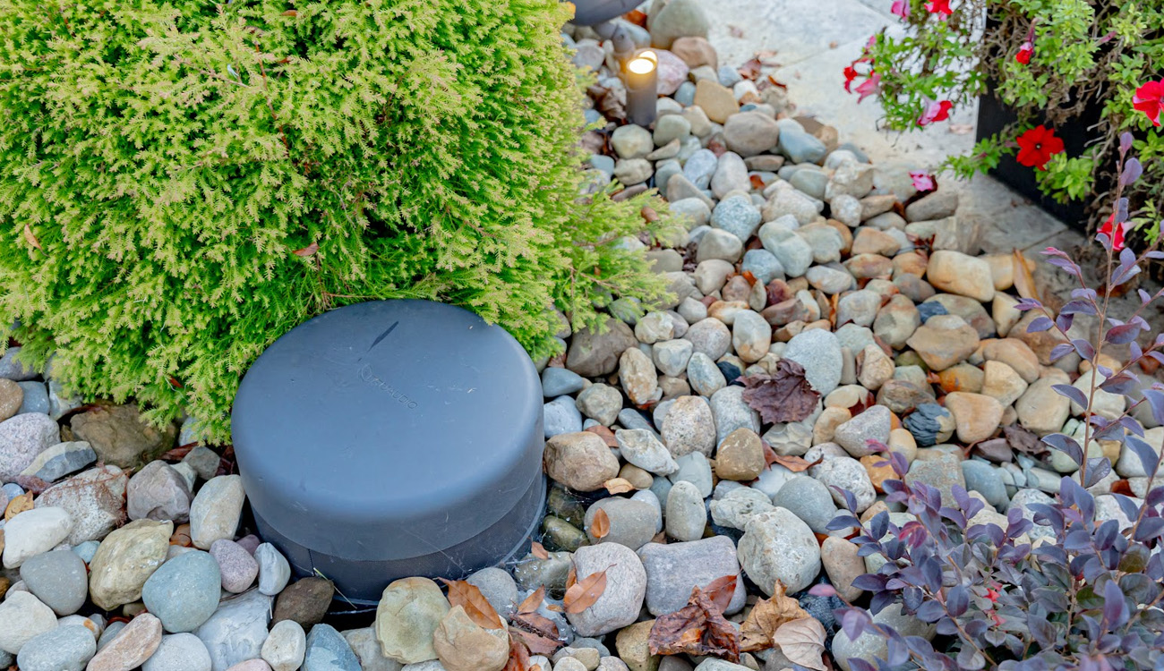 Low-profile outdoor speaker nestled in a stone planting bed