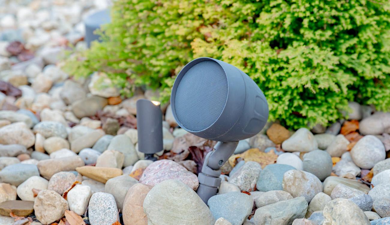 Landscape speaker mounted beside rocks and shrubs