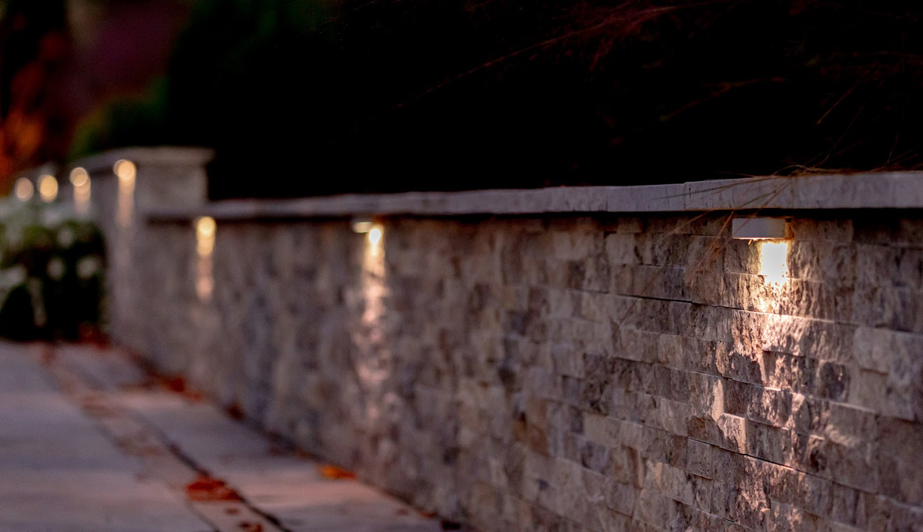 Downward-facing lights along a stone retaining wall