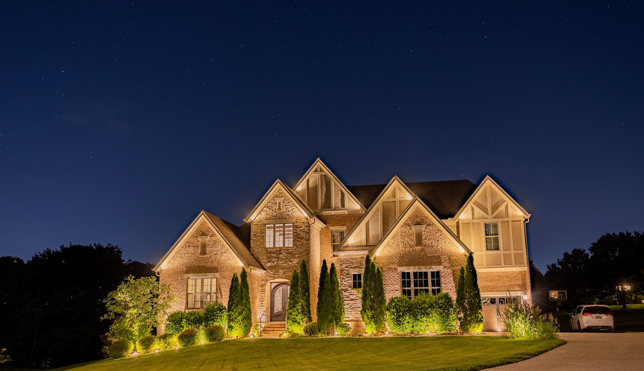 Uplighting highlighting a home's stone facade and gables