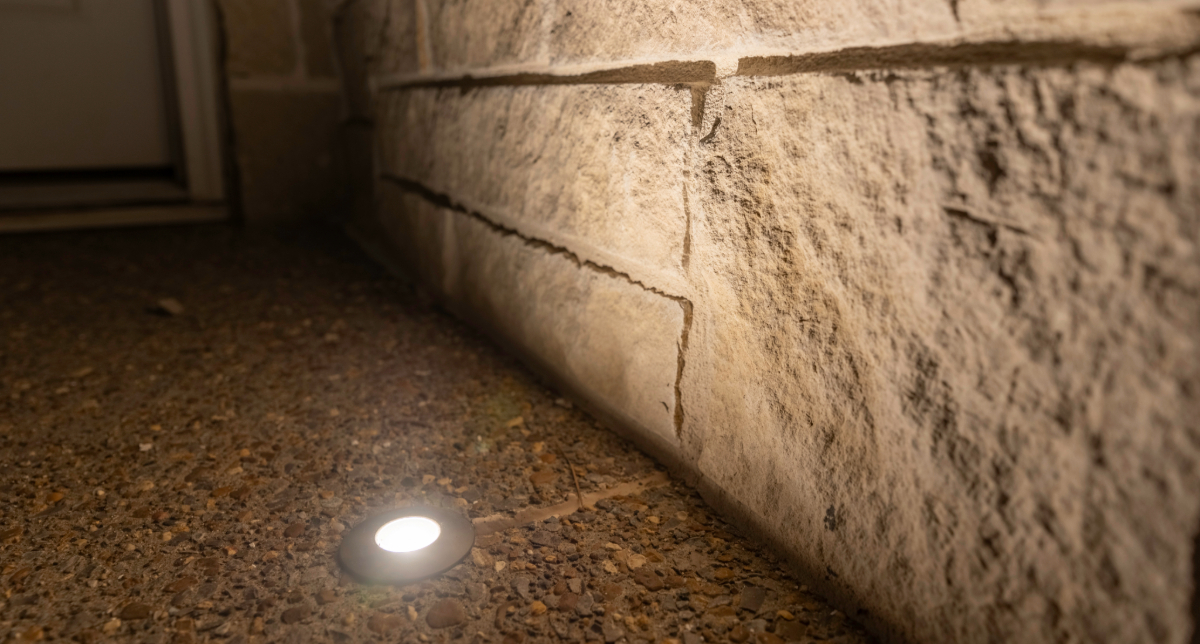 Recessed ground light beside a textured stone wall