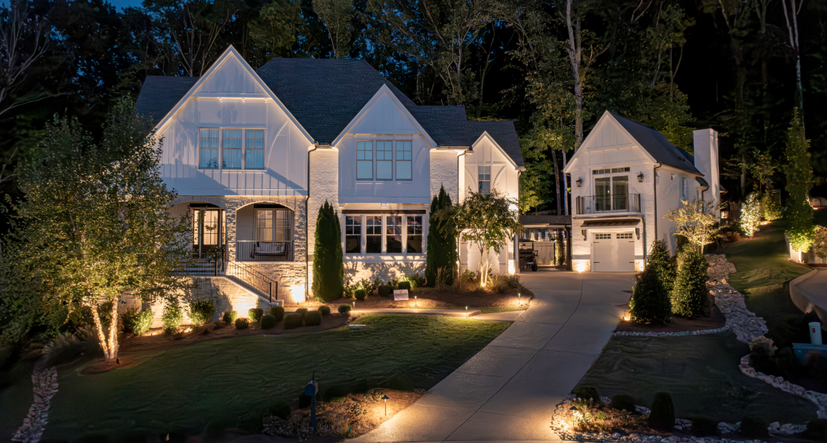 Home facade and front garden illuminated at dusk