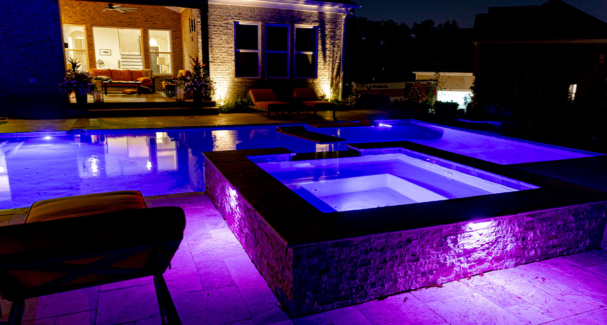 Blue and purple lights illuminating a pool and spa