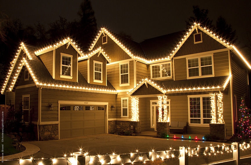 Holiday lights outlining a home's roof and front garden