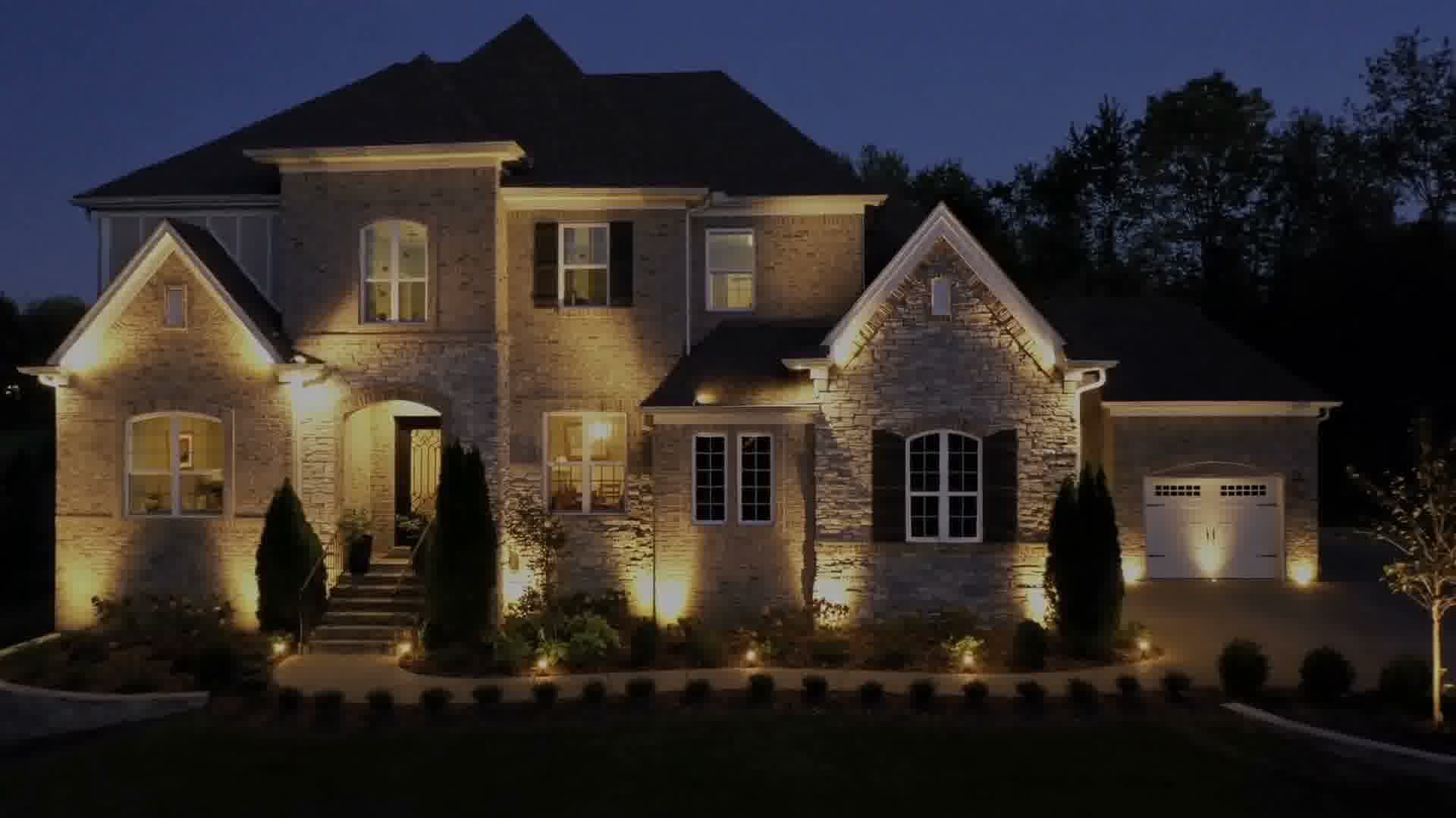 Warm outdoor lighting illuminating a brick and stone home at night